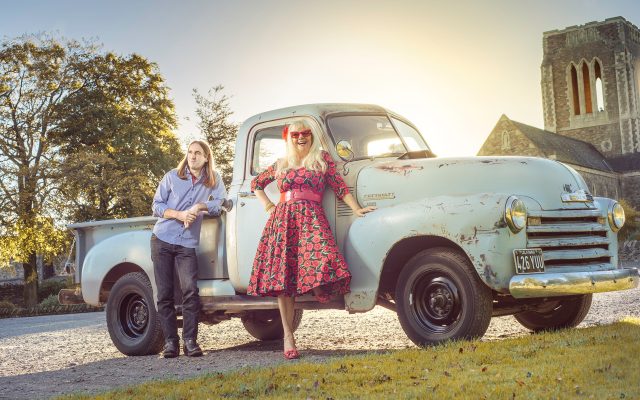 Annie Duggan and Rob Hines stood in front of a classic car on a road